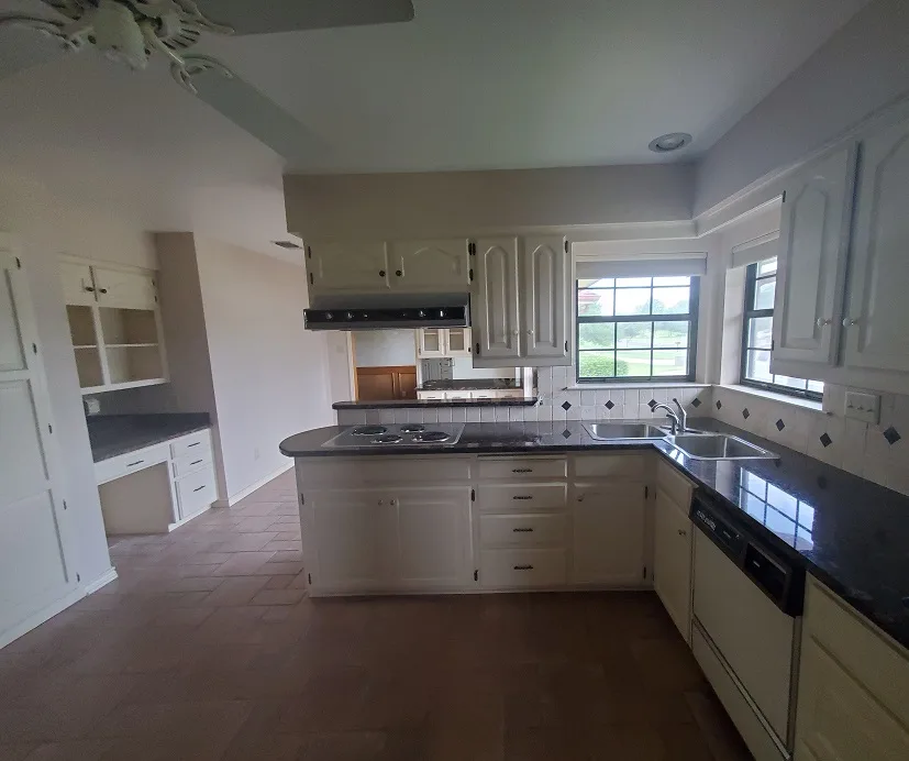 Kitchen in Gainesville, Texas with white cabinets and dark countertops