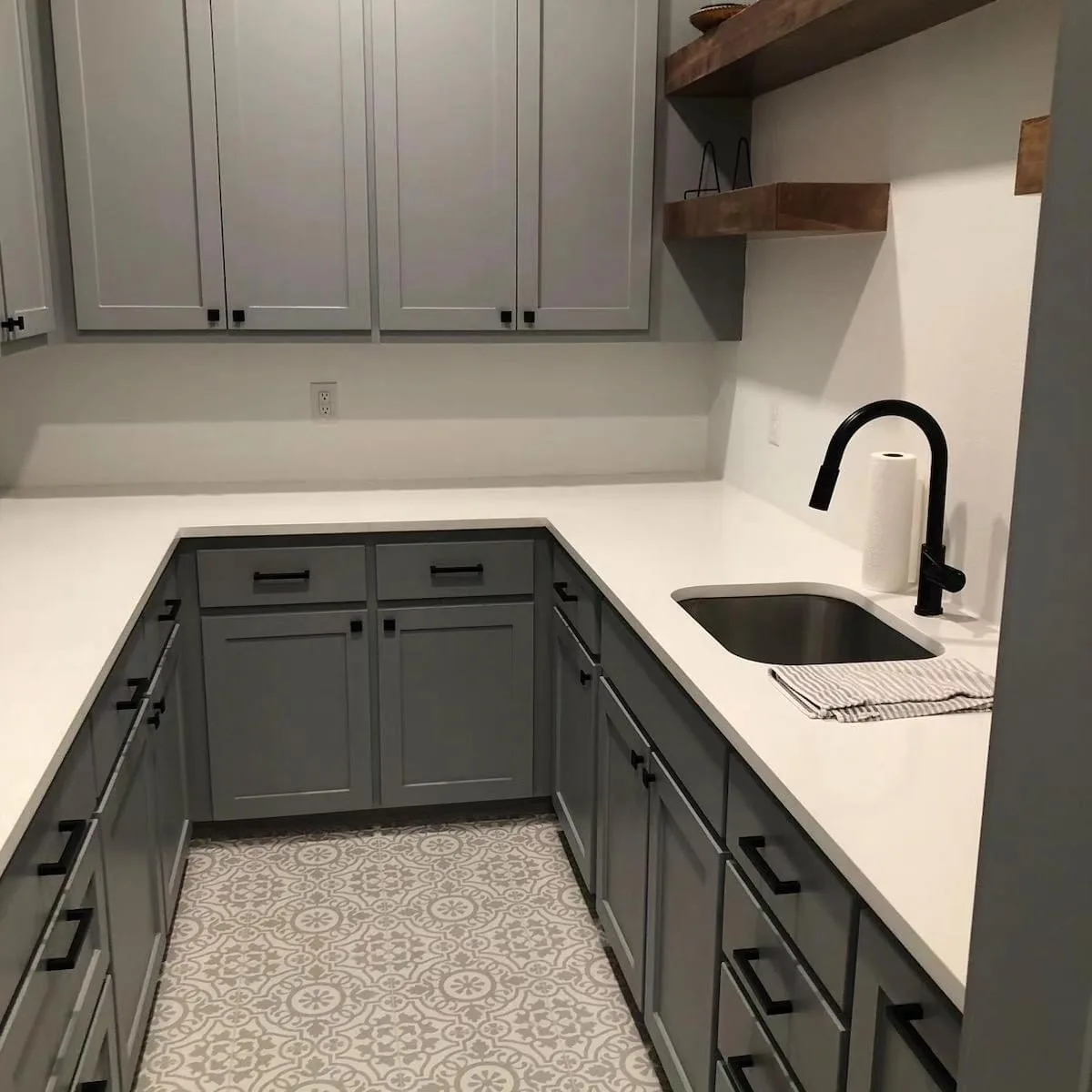 Utility room with gray cabinets, a black faucet and patterned tile floor