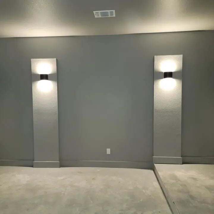 Gray media room wall with two lit wall sconces