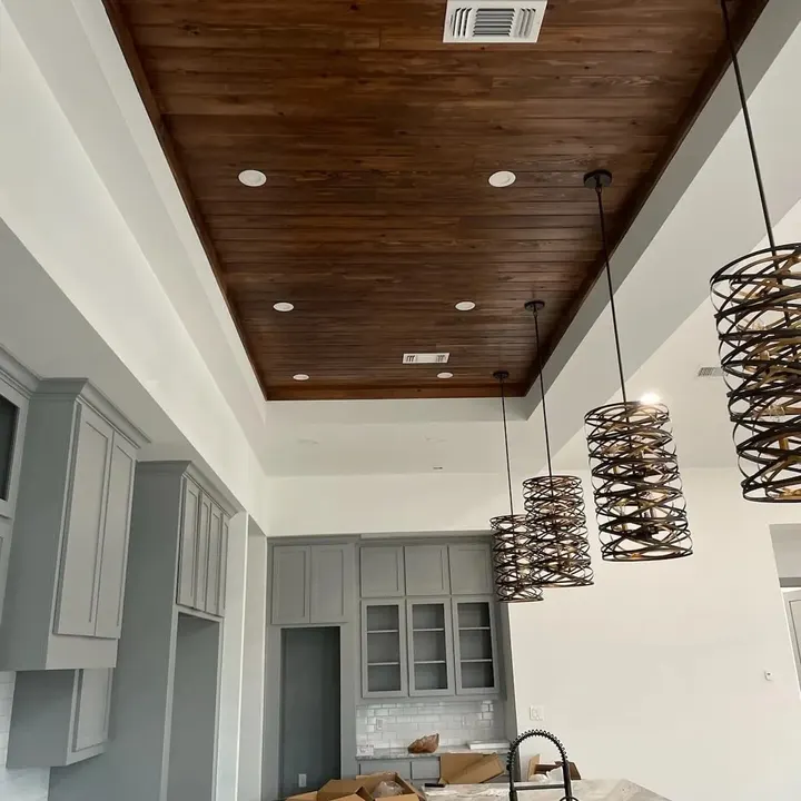 Wood-plank tray ceiling with recessed lights over gray kitchen cabinets and spiral pendant lights